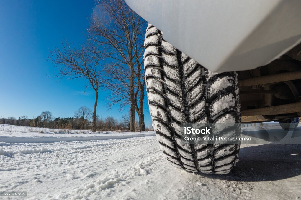 Detailed view of a winter tire providing traction on a snowy road, emphasizing driving safety