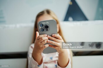 Child's hands holding a modern smartphone covering face. Focusing on technology, screen time, and digital native youth